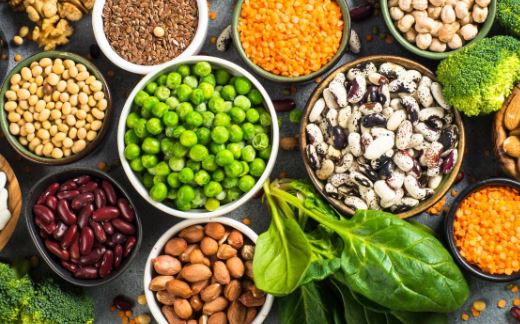 Various plant-based protein sources including lentils, tofu, quinoa, and nuts on a wooden table, representing vegan protein options.